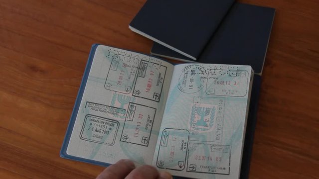 the Police Officer Looks in Passport Stamps of Crossing of Borders