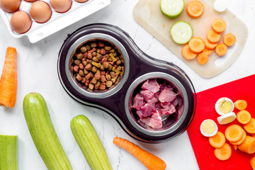 Dogfood, eggs, meat, carrot and courgette on table background top view