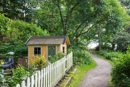 Liten gul lekstuga p&aring; en tomt p&aring; L&aring;ngholmen vid strandpromenaden. L&aring;ngholmen &auml;r en  lummig och fina &ouml; i centrala Stockholm (2 av 2)