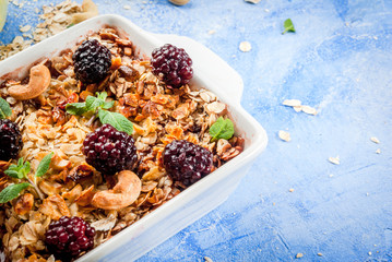 Freshly baked diet berry crumble with oatmeal with fresh berries blackberries decorated with mint leaves. In a frying pan for baking, with ingredients on blue stone concrete table copy space