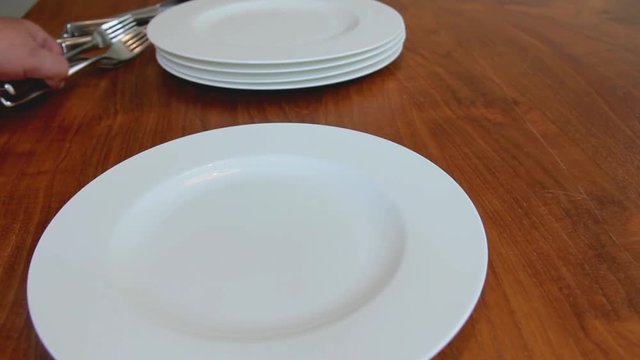 Male Hands Arranging Porcelain Plates and Tableware on a Brown Wooden Table