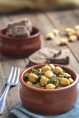Chickpea and spinach stew on rustic wooden background. Spanish cuisine.