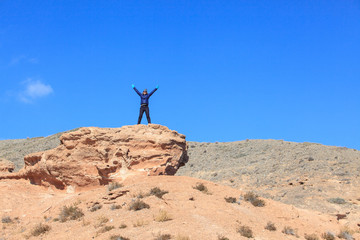 Happy woman standing on the top of the hill with raised hands  and enjoy the view 

