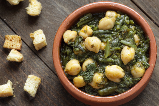 Chickpea and spinach stew on rustic wooden background. Spanish cuisine.