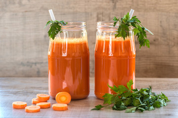 Fresh carrot juice in bottles on a grey wooden table