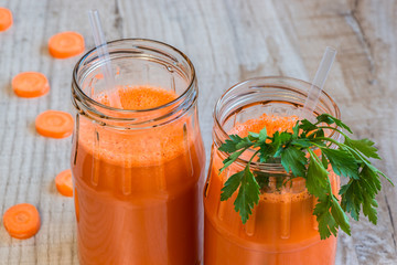 Fresh carrot juice in bottles on a grey wooden table