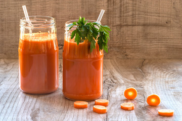 Fresh carrot juice in bottles on a grey wooden table