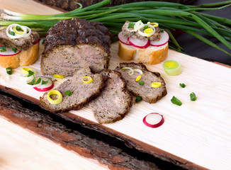 Liver pate with chives, radish and leek on a wooden board