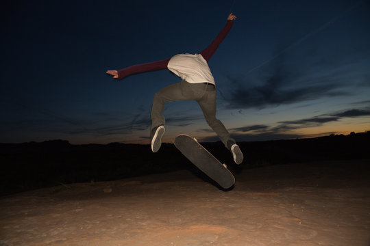 Rear view of skateboarder in mid air doing skateboarding trick