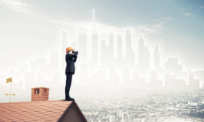 Fototapeta na wymiar Engineer man standing on roof and looking in binoculars. Mixed m