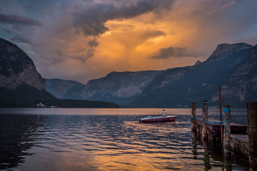 Fototapeta na wymiar A man in a boat on the lake on sunset in Austria