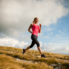 runner - woman runs cros country on a path in early autumn