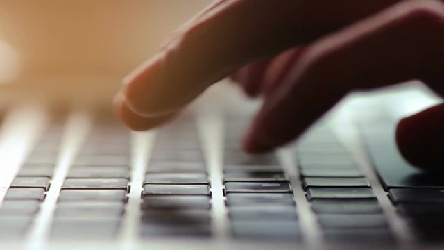 macro shot of a male hands typing on laptop keyboard