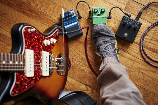 a person playing a guitar and using effect pedals