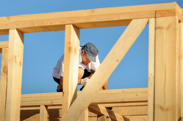 The young man, a builder builds a wooden frame house