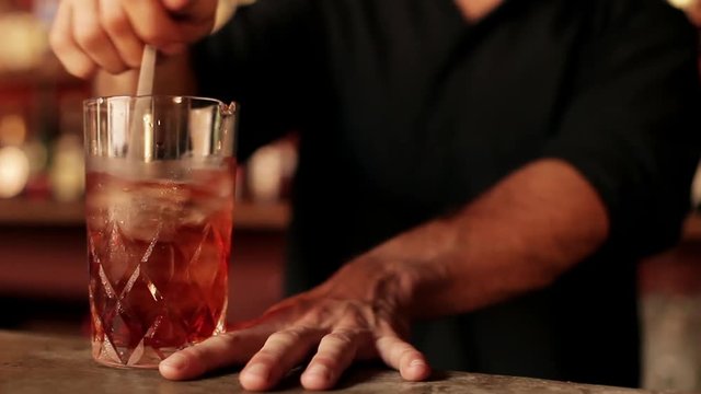 Bartender stirring negroni in glass