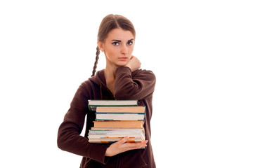 stylish serious brunette student girl with pigtails in brown sports clothes with books in her hands looking at the camera isolated on white background