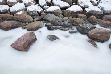 Rocky beach frozen in winter day. Stones decorated with ice. Environment is calm. 