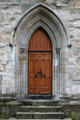 Fototapeta na wymiar Fassadendetail mit Portal und hölzerner Tür aus der Gotik an der Domkirke von Bergen, Hordaland, Norwegen