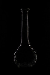 Obraz na płótnie Canvas Glass bottle on a black background. Silhouette of bottle reflects light, promotional photo. Laconic minimalism, creative photo of a glass bottle. Abstraction, contours of bottle