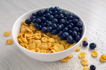 granola with blueberries in white bowl on wooden white background