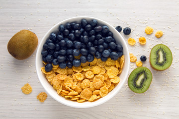 granola with blueberries in white bowl on wooden white background