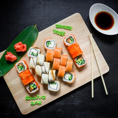 Japanese food - sushi rolls and sauce on a black wood background. Top view. Flay lay