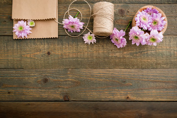 Obraz na płótnie Canvas Pink flowers and twine, craft paper on rustic wood background. Flat lay, top view. Art background