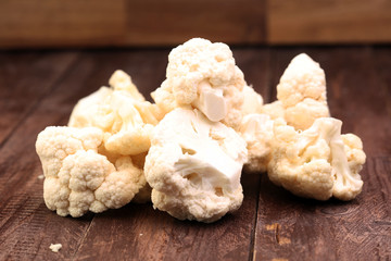 Fresh organic cauliflower cut into small pieces on wooden background