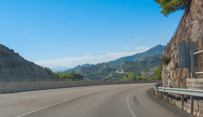 Around the bend - Sunshine on Spanish coastal highway.   Driving view of foothills and mountain ranges on the edges of continental Europe in Spain.