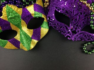 Mardi Gras masks and beads on a black surface
