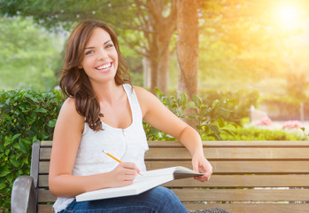 Obraz premium Attractive Young Adult Female Student on Bench Outdoors with Books and Pencil.