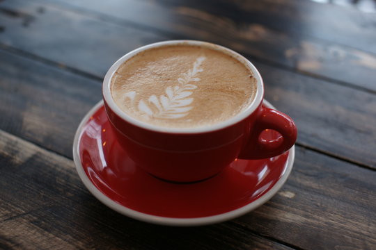 A Large Red Coffee Mug On A Wooden Table.