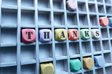 Thanks word made with building wooden blocks / Composition of the word Thanks with wooden cubes in square box