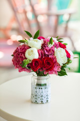 Wedding bouquet roses and peonies in glass vase on table