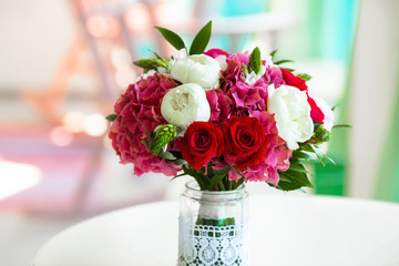Wedding bouquet roses and peonies in glass vase on table