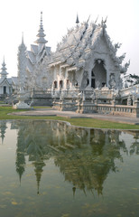 Obraz premium CHIANG RAI, THAILAND - February 27, 2010: beautiful and amazing Wat Rongkhun (White temple) is reflected in the lake. White temple, Chiang Rai, Thailand.