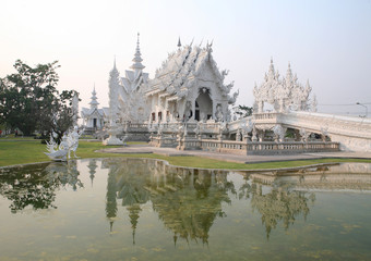 Fototapeta premium CHIANG RAI, THAILAND - February 27, 2010: beautiful and amazing Wat Rongkhun (White temple) is reflected in the lake. White temple, Chiang Rai, Thailand.