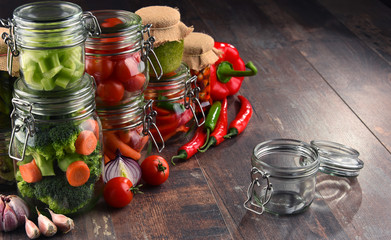Jars with marinated food and organic raw vegetables