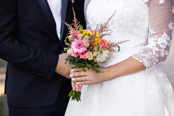 Bride and groom holding wedding bouquet of fresh flowers. Wedding concept