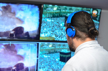 Video broadcast editor with headphones watching an action on the monitor. Live TV broadcasting process.