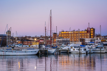 Fototapeta na wymiar Buildings and boats docked on the Canton Waterfront at twilight, in Baltimore, Maryland.