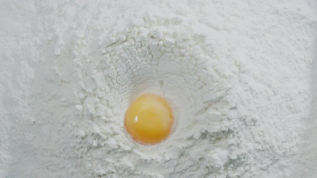 Slow motion of falling eggs into flour stock. Footage food. Egg dropping into flour, slow motion. Yolk Falls Into the Flour. Food Blog, Flour Products. Bakery products. Preparation of the dough