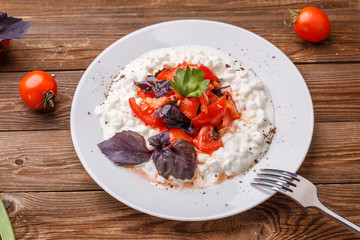 Salad with cottage cheese and tomatoes on wood table.