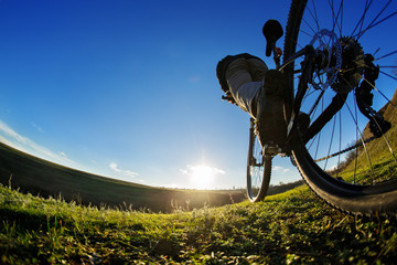 Fototapeta na wymiar Detail of cyclist man feet riding mountain bike on outdoor trail in sunny meadow