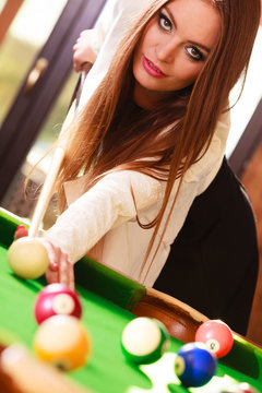 Young fashionable girl playing billiard.