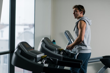 Young, handsome man  using treadmill in the gym