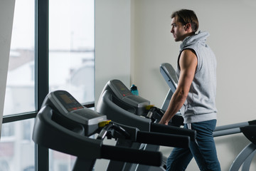Fototapeta na wymiar Young man exercising on treadmill at the gym