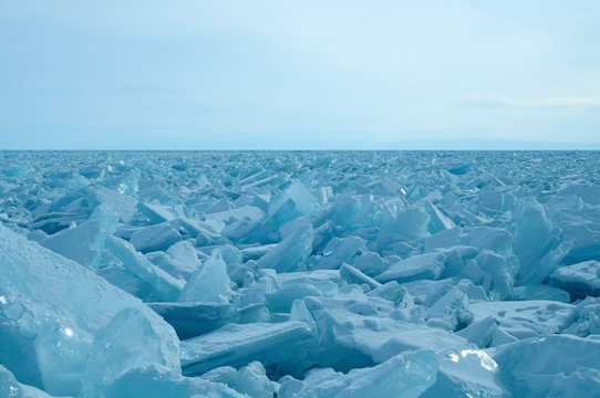 ice hummocks on the northern shore of Olkhon Island on Lake Baikal. Transparent blocks of crystal clear ice crawl ashore. Colorful refraction of rays of rising sun. Ice Storm. Photo partially tinted.
