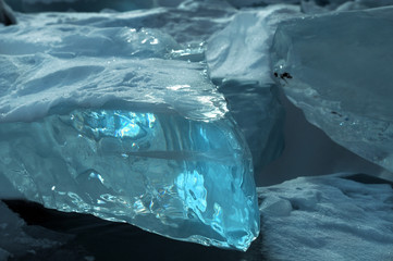 ice hummocks on the northern shore of Olkhon Island on Lake Baikal. Transparent blocks of crystal clear ice crawl ashore. Colorful refraction of rays of rising sun. Ice Storm. Photo partially tinted.